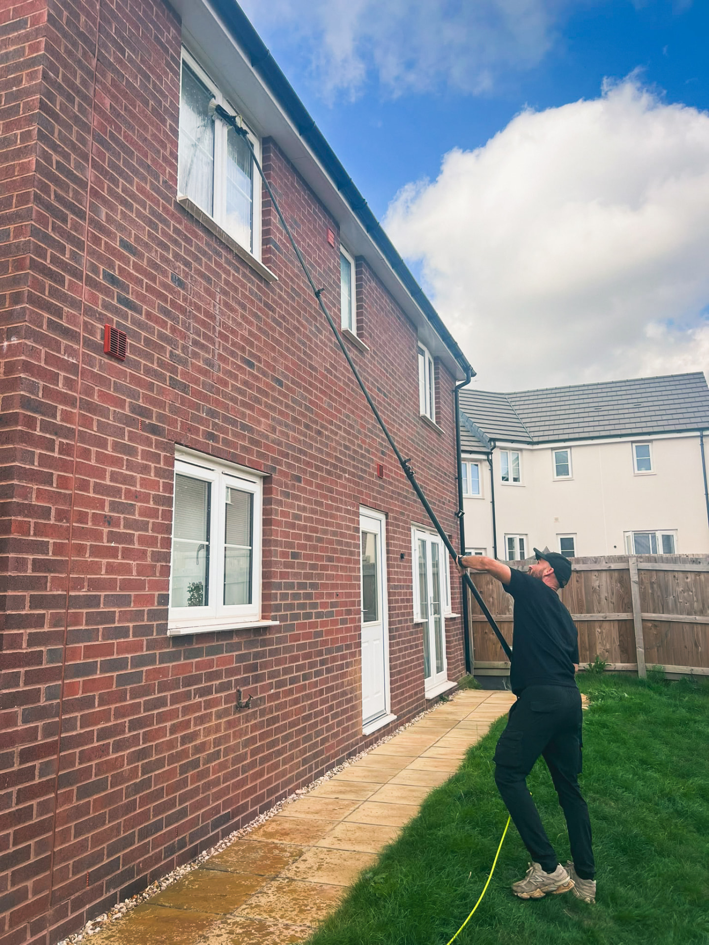 Window cleaner using a water-fed pole on a new-build home in Tithebarn