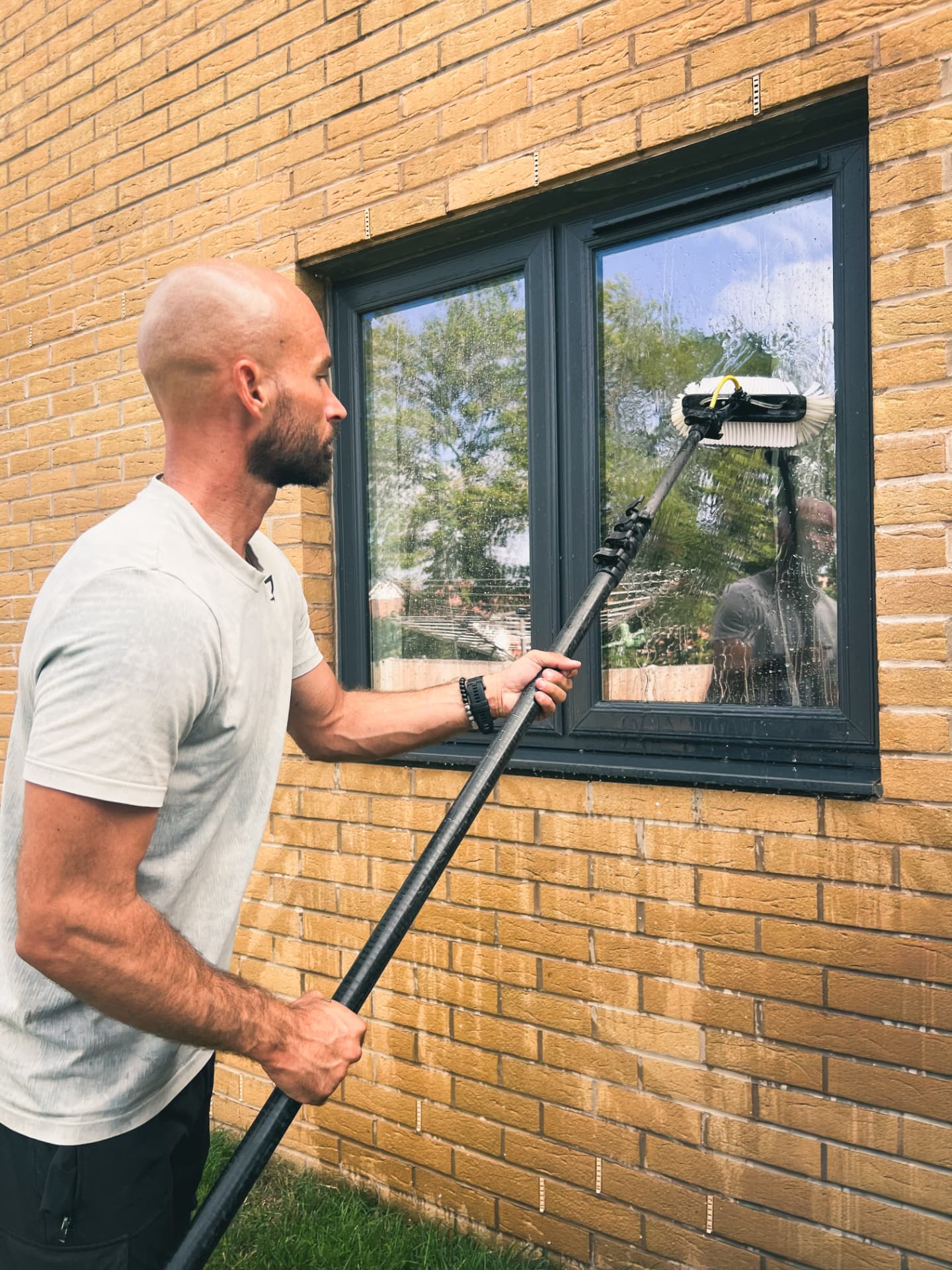 Window cleaner using a water-fed pole to rinse a first-floor window
